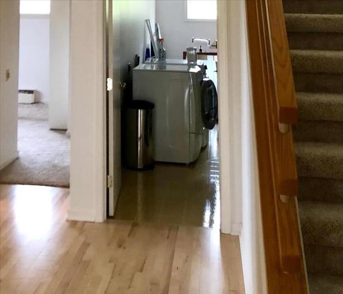 A remodeled hallway with restored hardwood floors leading to laundry room 