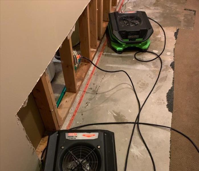 a room with flood cut drywall with green servpro humidifiers and air movers