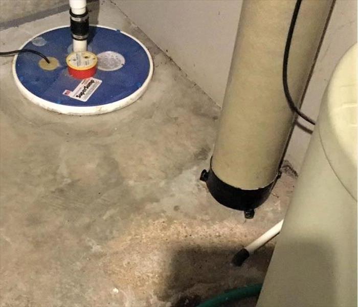 a concrete basement floor with sump pump and water heater 