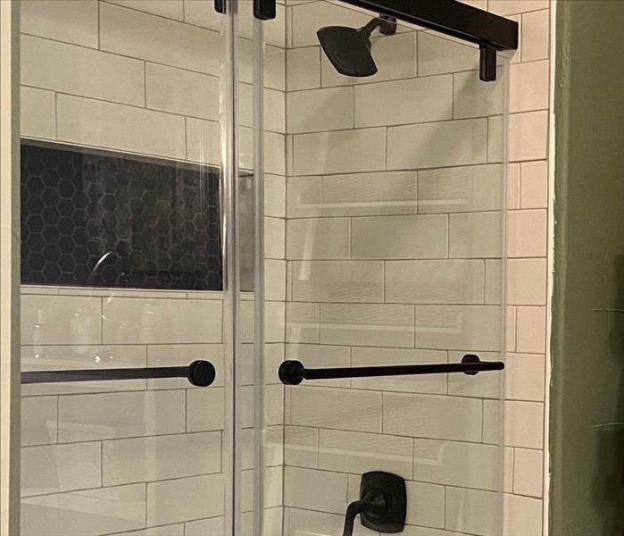 a shower remodel with white subway tile and glass doors after a water loss