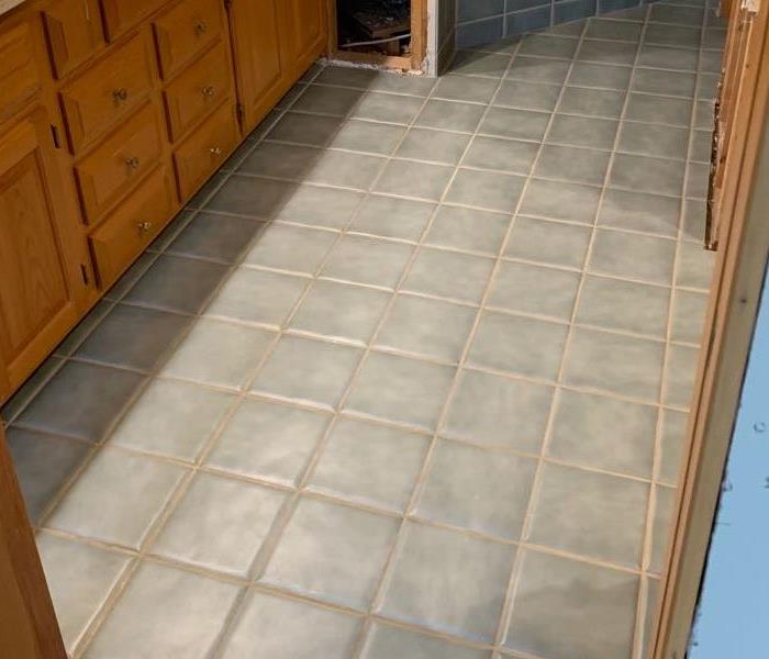 a bathroom with grey tile that was saved from water damage after a toilet leak