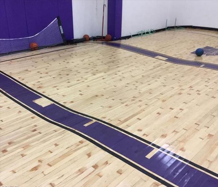 a water-logged sport court exhibiting extreme floor buckling from water damage
