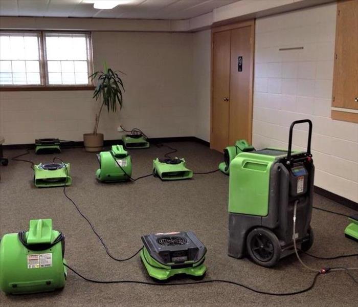 commercial carpet being dried with many green air movers and a large green humidifier 