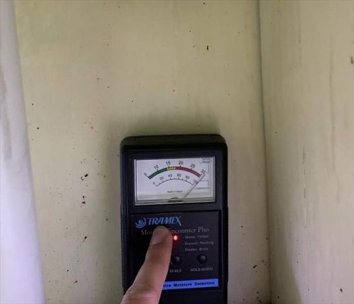 a moisture meter showing extreme moisture saturation of a wall