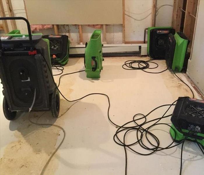 a basement with servpro air movers and dehumidifiers to dry out a water damaged basement
