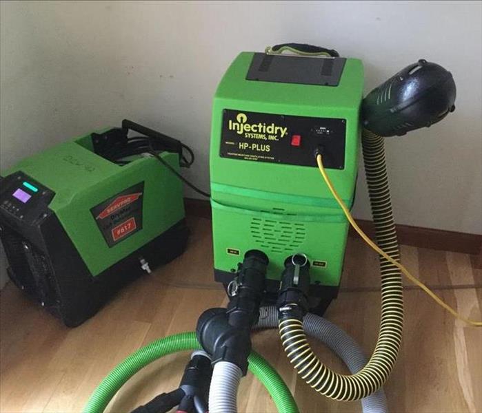 two servpro green injector dry machines used to dry and save buckled hardwood floors