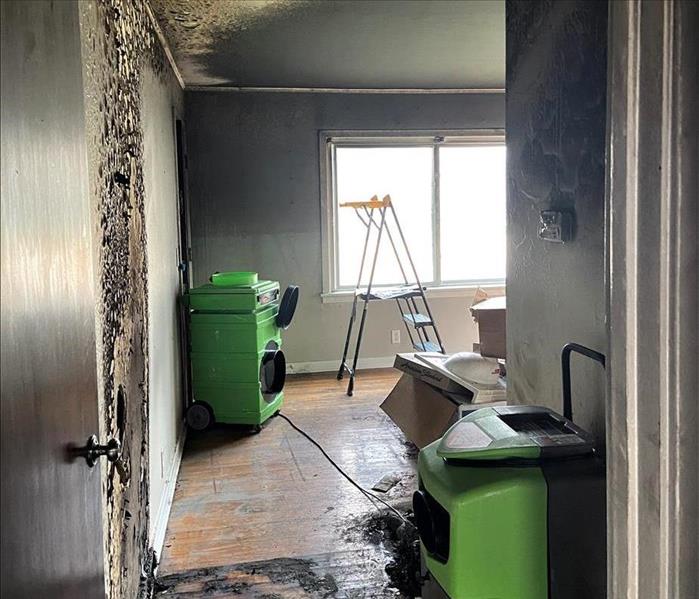 a fire damaged hallway of a hallway to front room in a apartment with extreme charring and fire damaged wall
