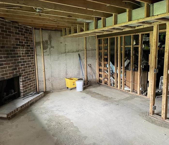 a family room with a brick fireplace after fire damage the drywall has been removed to studs 