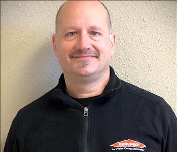 a headshot of a Caucasian man in a black zip up pullover with a SERVPRO logo on it