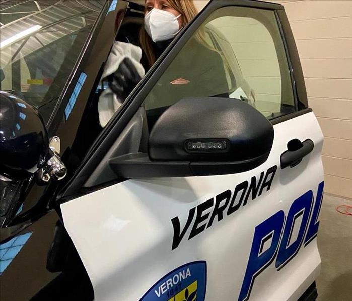 a woman in protective mask sanitizing verona police squad car