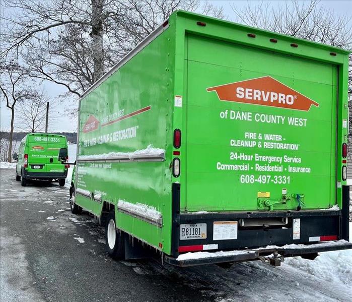 two servpro green trucks parked on a snow covered street 