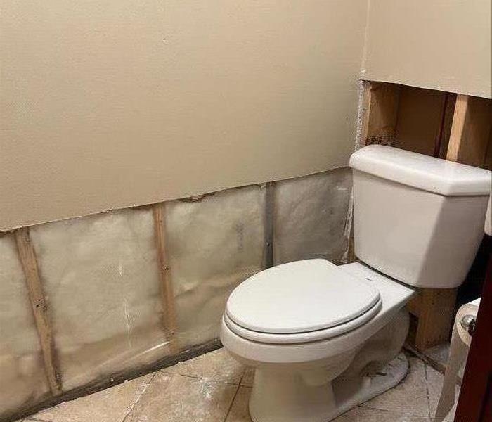 a neutral colored bathroom with tile floors and flood cut drywall from sewage damage 