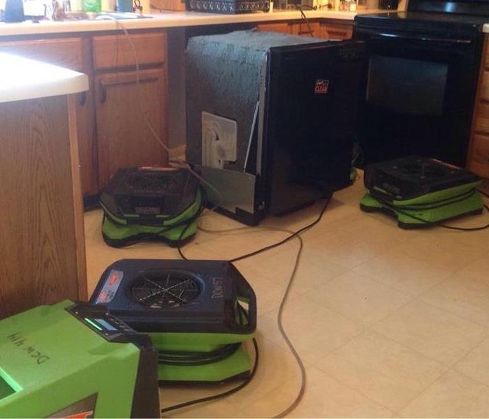a kitchen with SERVPRO green air movers and dehumidifier to dry water damage 