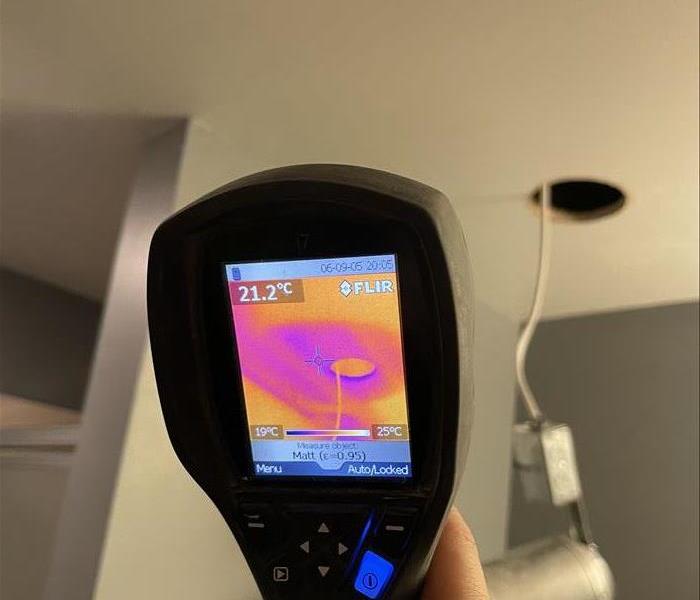 close up of a thermal camera detecting water damage in a ceiling corner 