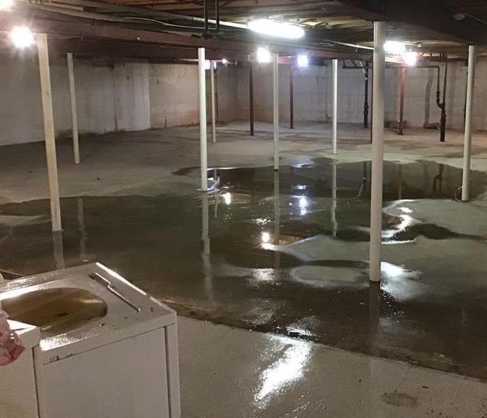 An unfinished basement of an apartment complex with pooling water from broken water pipes from units above 