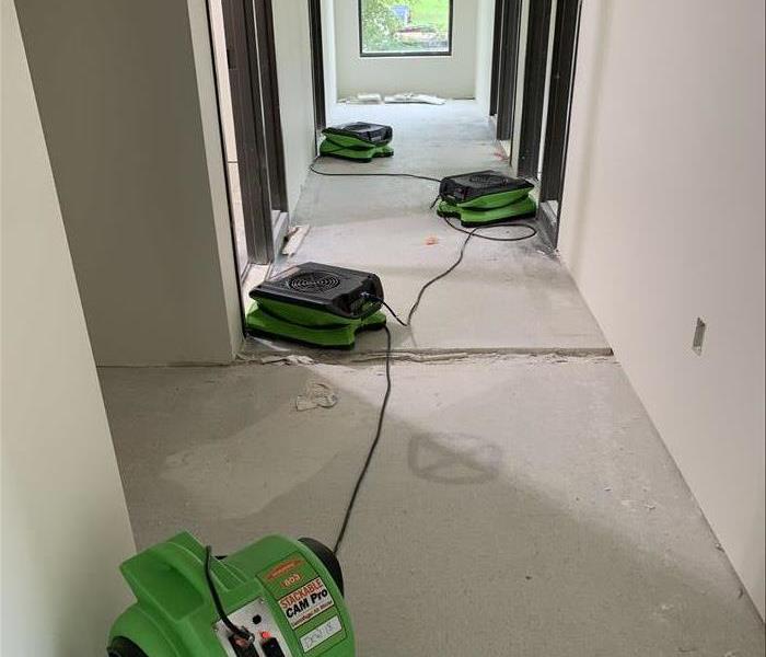 hallway of an office building under construction with 4 servpro green air movers drying in place