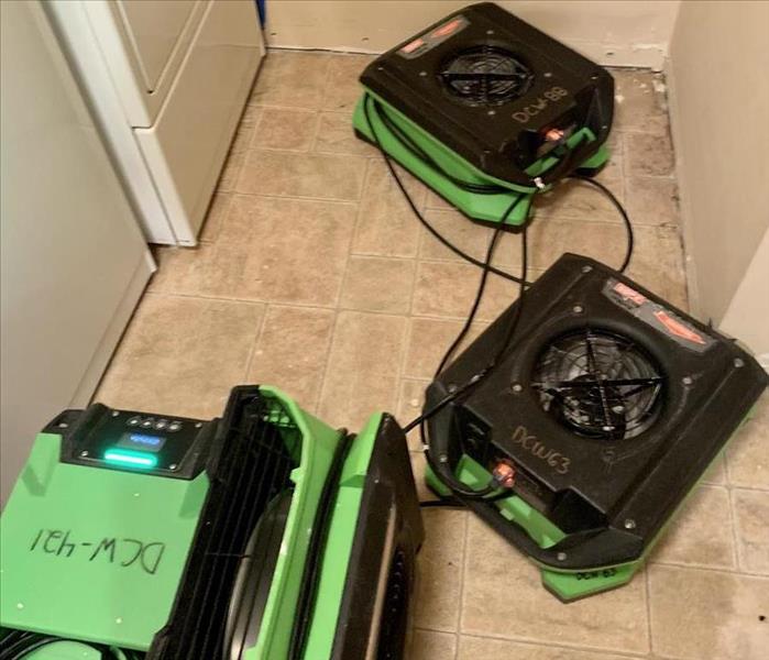 a laundry room with servpro green air movers and dehumidifiers in place to dry the water damage 