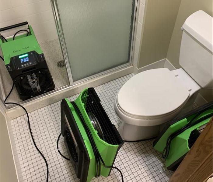 a bathroom with servpro air movers in place to dry the room from water damage from a broken water line 