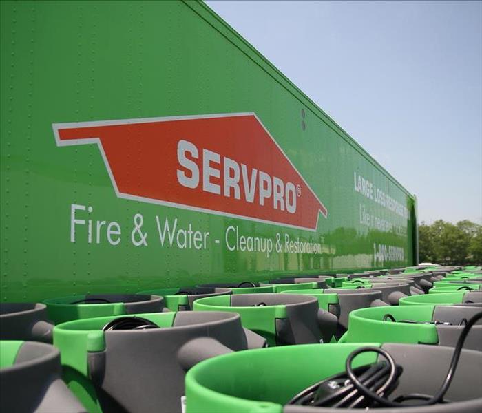 large green servpro semi truck with stacks of green air movers next to it