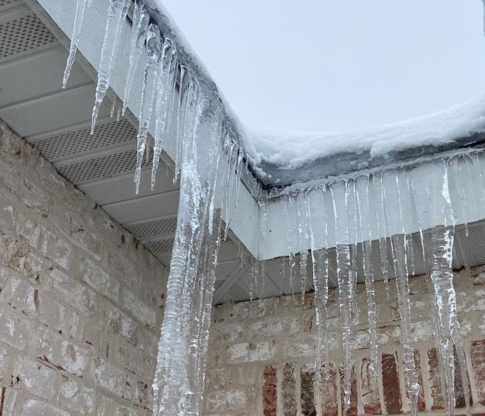 icicles dripping down a white brick house 