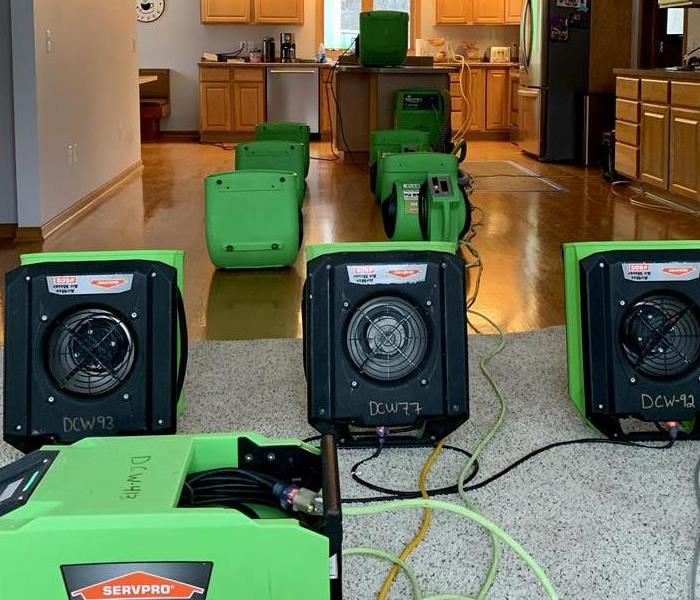10 servpro green air movers and dehumidifiers placed in kitchen to dry water damaged area
