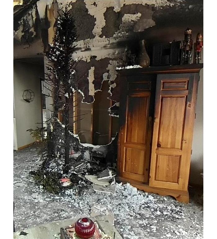 a burnt christmas tree in a family room affected with charred walls, ceilings and furniture